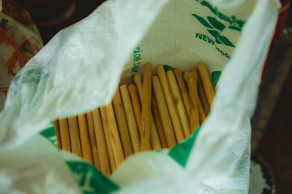 Several wooden sticks neatly arranged inside a white bag, offering a rustic and traditional vibe.